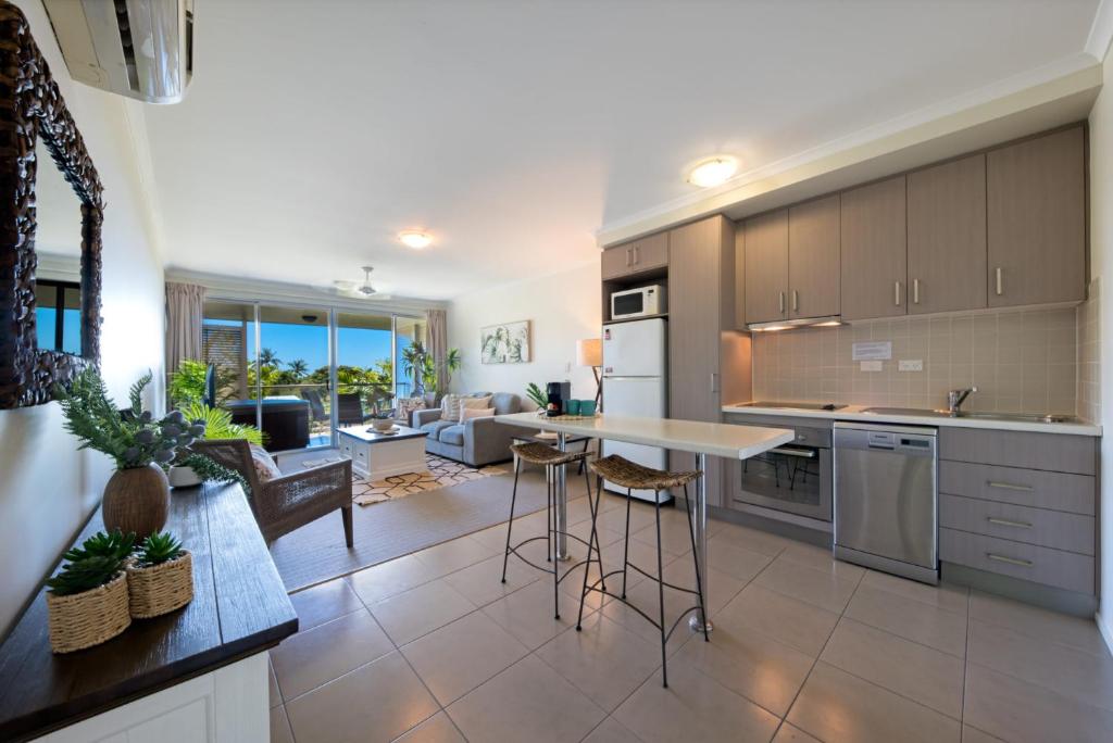 a kitchen and living room with a table and chairs at Waterlily - Two Bedroom Apartment in Airlie Beach