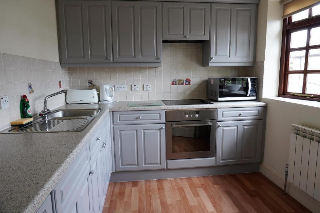 a kitchen with white cabinets and a sink and a microwave at The Uplands Apartments in Saint Helier Jersey