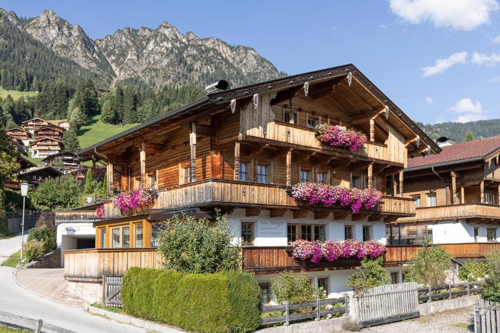 a large wooden house with flowers on the balconies at Wellnessappartements Margit in Alpbach