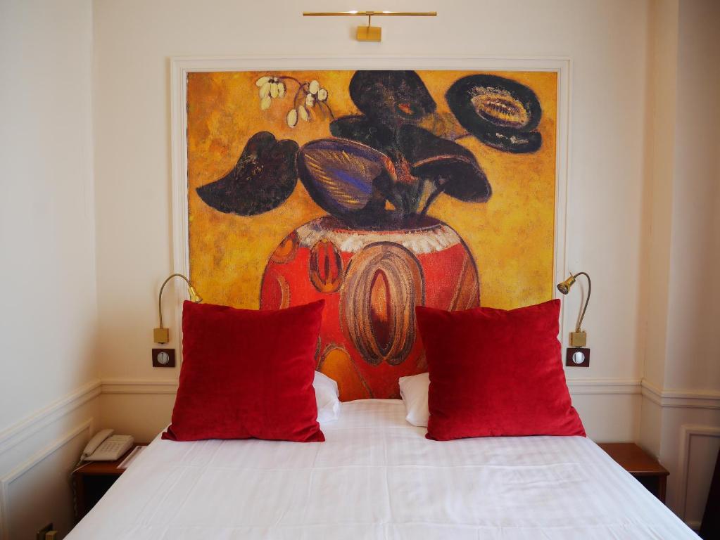 - un lit avec des oreillers rouges devant un tableau dans l'établissement Timhotel Tour Montparnasse, à Paris