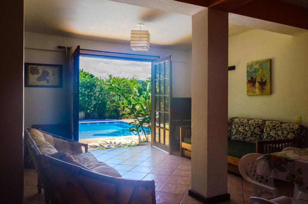 a living room with a view of a swimming pool at Casa Ilhabela - melhor custo benefício in Ilhabela