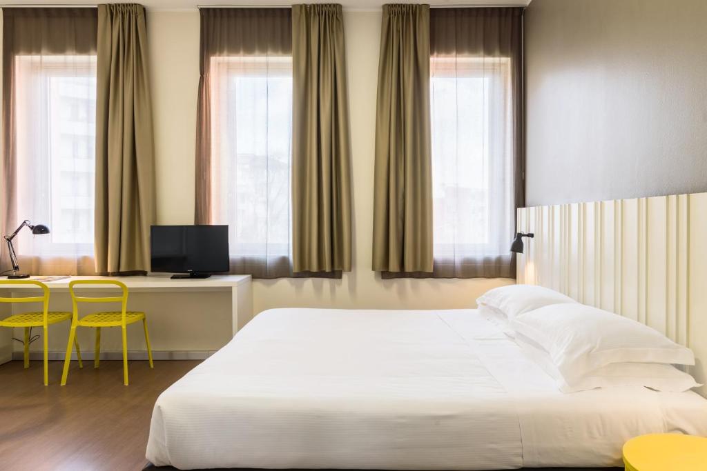 a bedroom with a bed and a desk and two chairs at B&B Hotel Milano Ornato in Milan