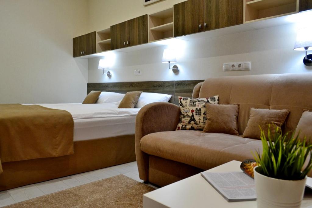 um quarto de hotel com uma cama e um sofá em Апартаменты Park & House 8 рядом с источником и парком em Essentuki
