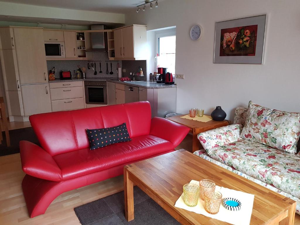 a living room with a red couch and a table at Ferienwohnung Mohnblume in Rosdorf