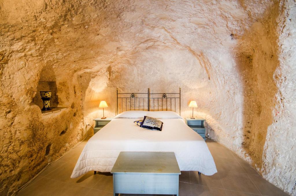 ein Schlafzimmer in einer Höhle mit einem Bett und einem Tisch in der Unterkunft Le Dodici Lune in Matera