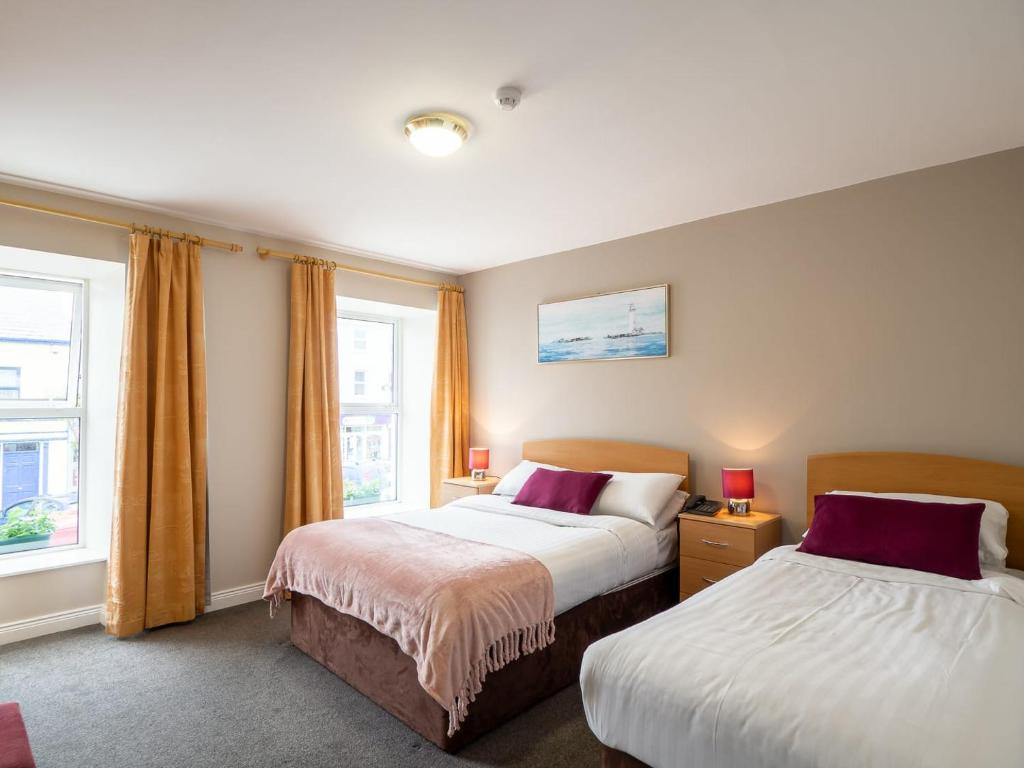 um quarto de hotel com duas camas e uma janela em The Woodfield Hotel em Clifden