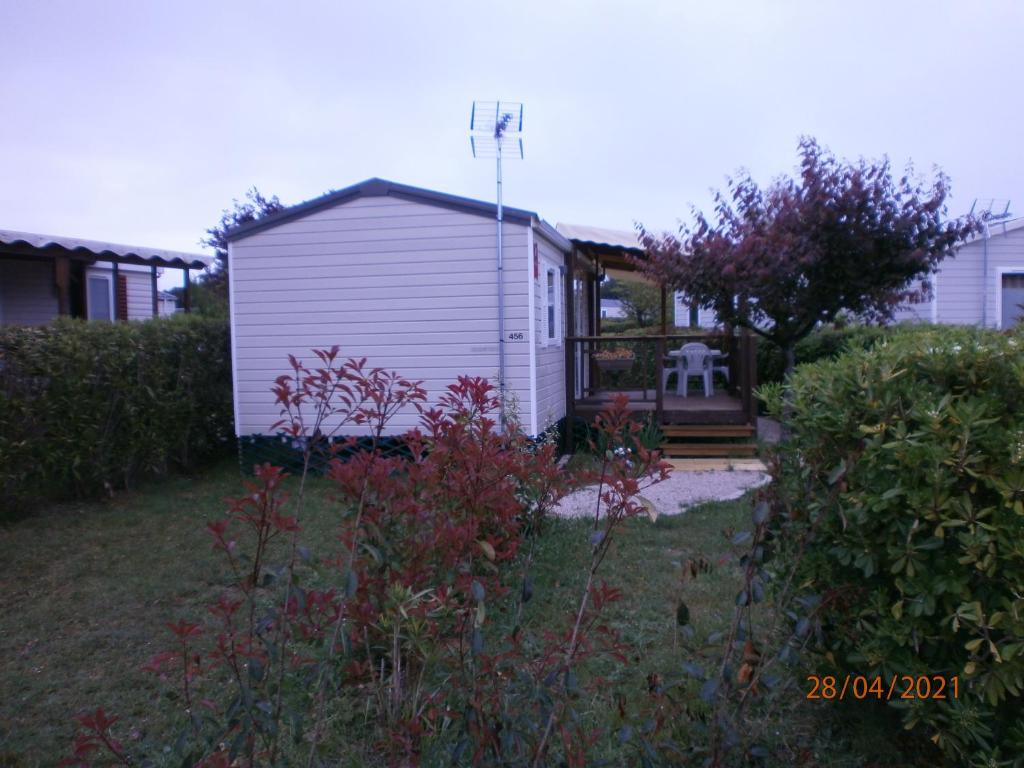 a small white building with a porch in a yard at Camping Le Lac des Rêves Lattes in Pérols