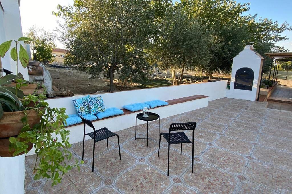 un patio con un banco, 4 sillas y una mesa en Casa Cactus Preciosa casa rural con piscina y exterior privado muy amplio, en Granada