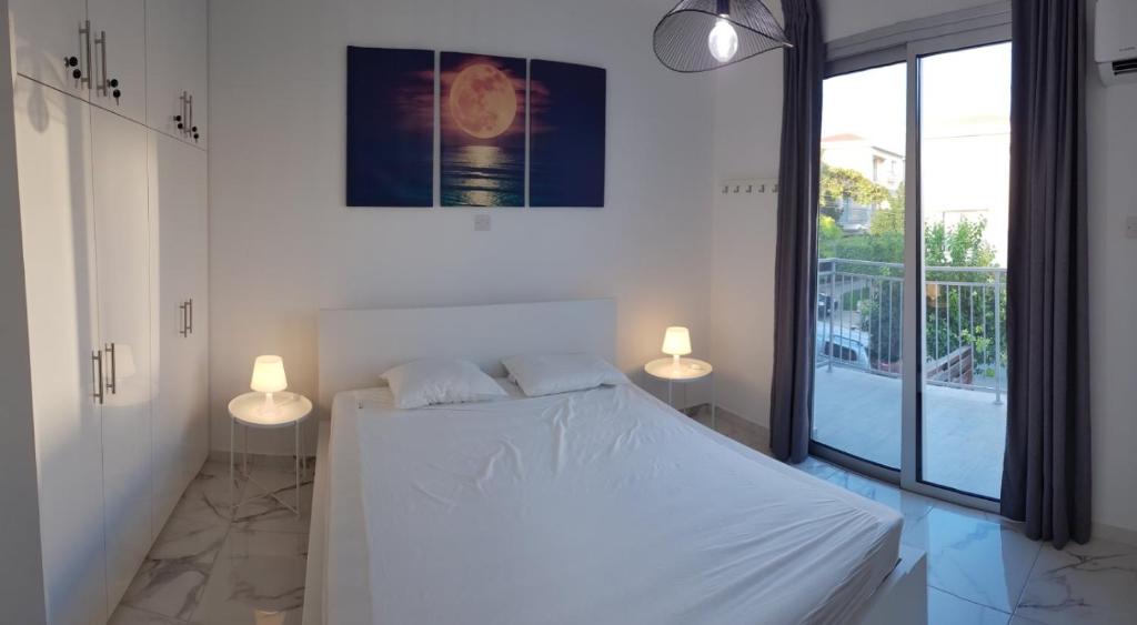 een slaapkamer met een wit bed en 2 lampen bij EROS Maisonette in Latchi area just 700 meters or one-minute drive from Polis Municipal Beach in Lachi