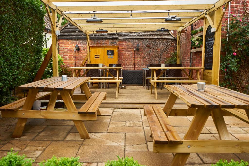 un patio con mesas de picnic de madera en un jardín en The Coachmakers Arms, en Wallingford