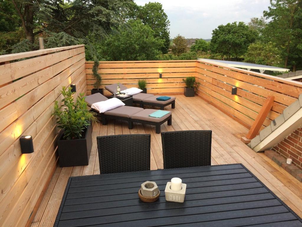 a patio with tables and chairs on a wooden deck at Ferienwohnung Wiebke -Ferien in Almdorf in Almdorf