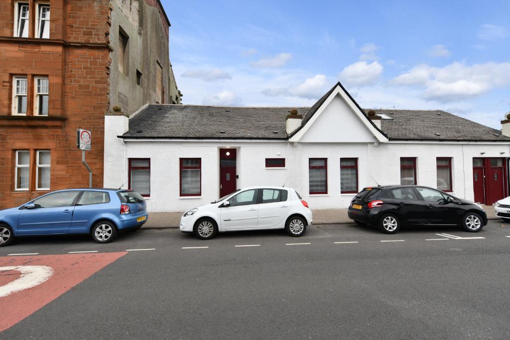 three cars parked in a parking lot in front of a building at Sunny Shores Cottage in Troon