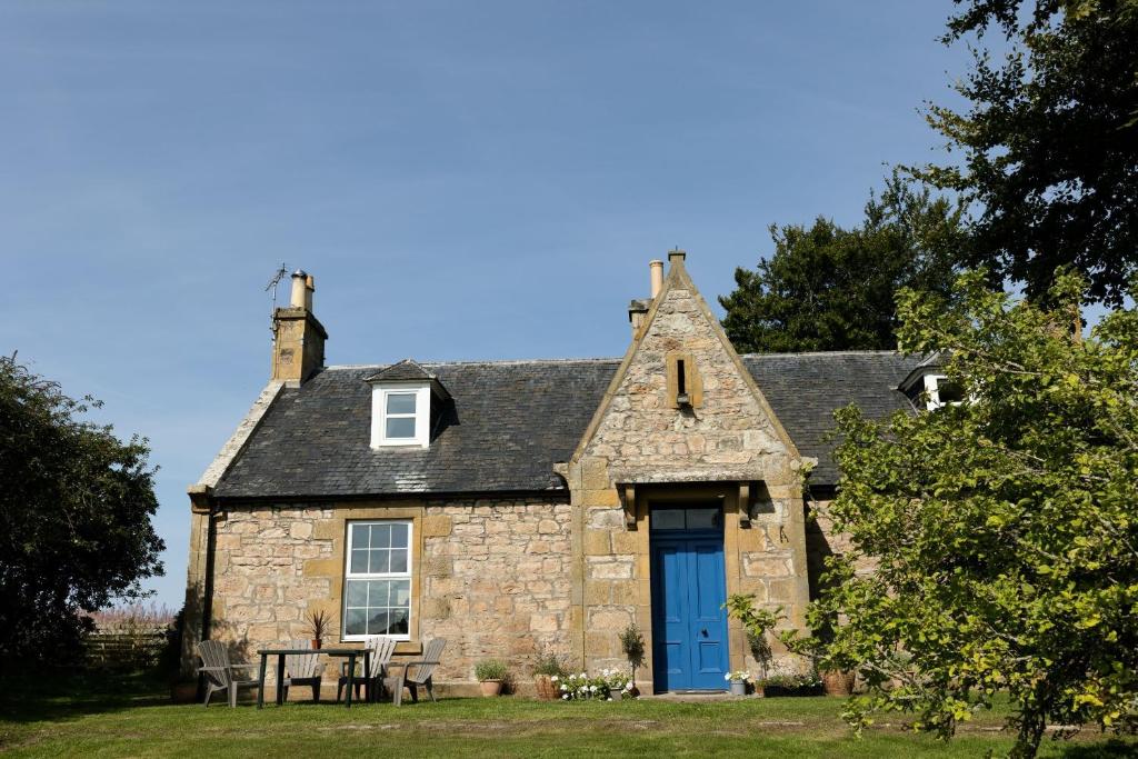 uma velha casa de pedra com uma porta azul em Abbotshill, Dalvey Estate em Forres