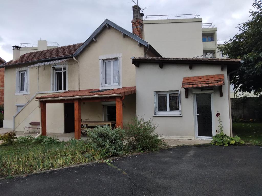 a white house with a porch and a garage at chambre d'hôte dans maison privée in Périgueux