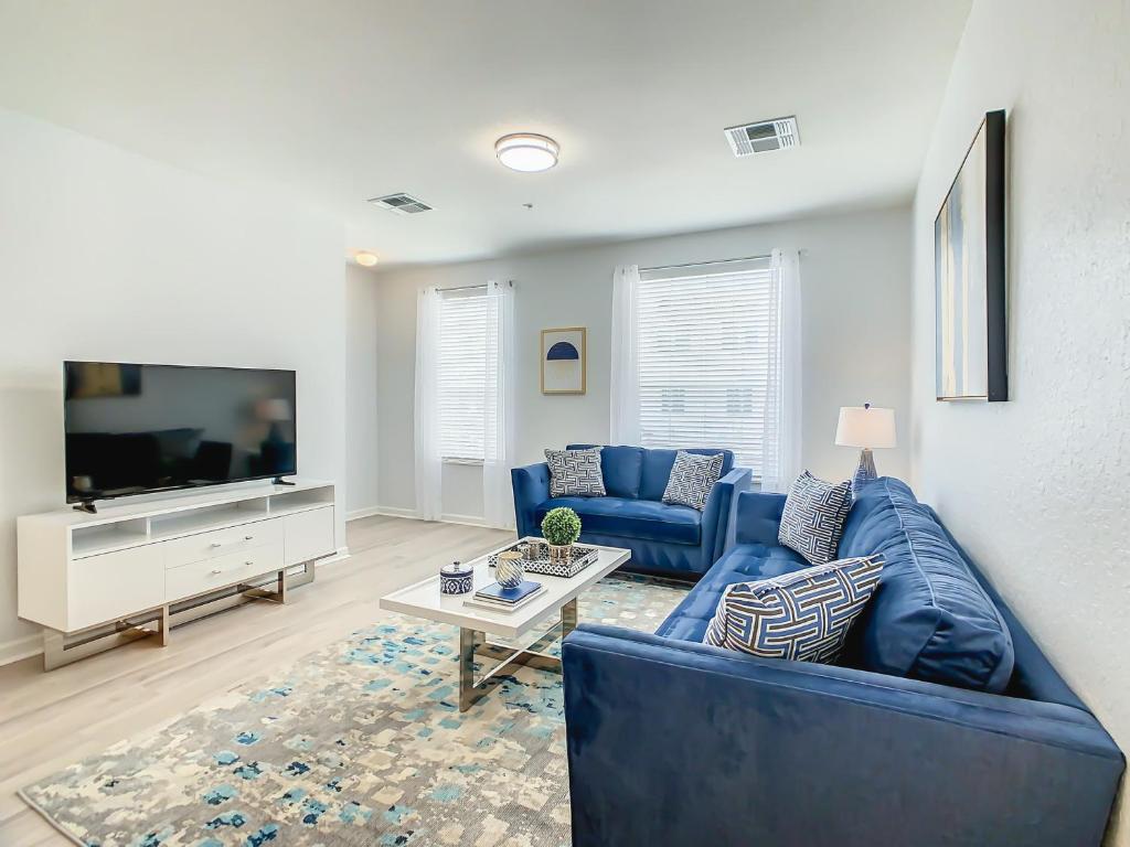 a living room with a blue couch and a tv at Stylish Vista Cay Townhome Near Conv. Ctr I-Dr. in Orlando