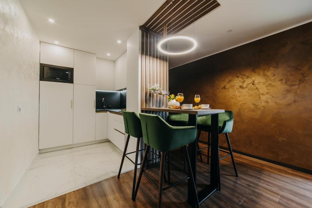 a kitchen with a table and green chairs at Apartman Stari Toranj in Vukovar