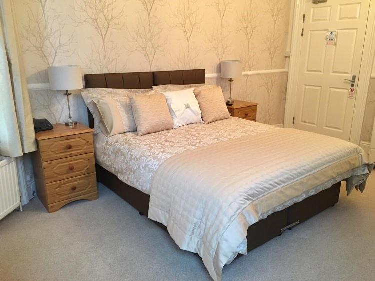 una camera con un letto e due comodini con lampade di Chaston Manor Hotel a Sandown