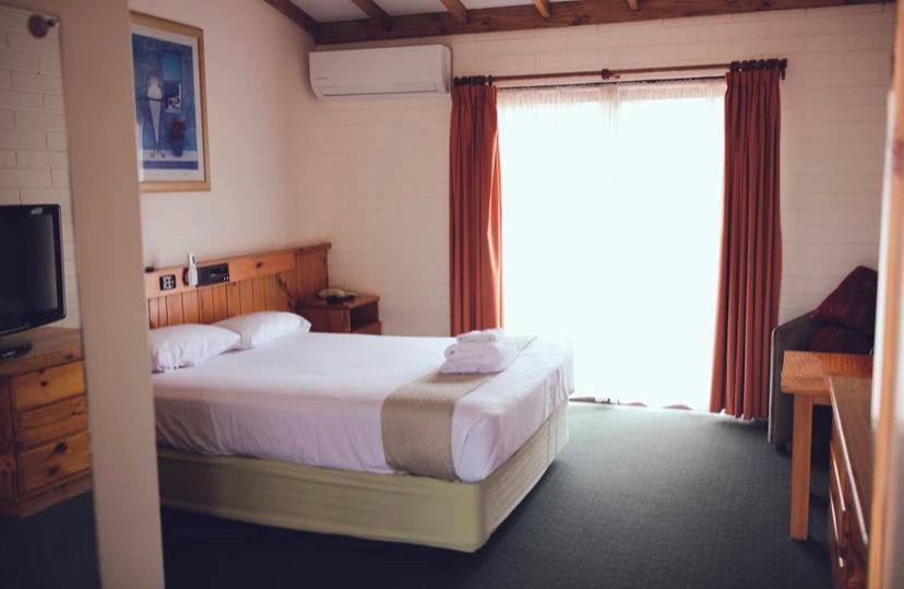 a bedroom with a bed and a large window at The Miners Rest Motel in Kalgoorlie