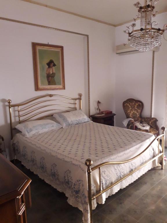 sypialnia z łóżkiem, krzesłem i żyrandolem w obiekcie Signorile appartamento in condominio Rallo w mieście Palermo
