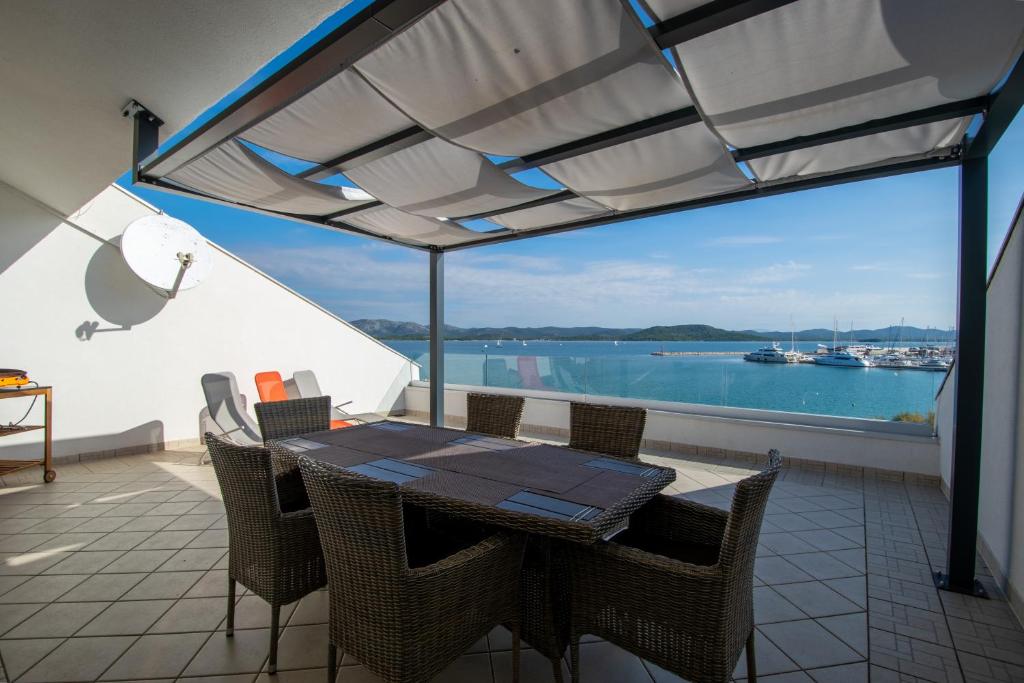 een patio met een tafel en stoelen en uitzicht op het water bij Apartments Lantina in Betina