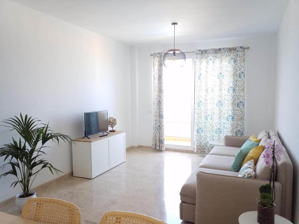 uma sala de estar com um sofá e uma televisão em Ocean View Playa Negra Apartment em Puerto de Santiago