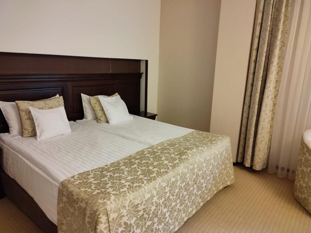um quarto com uma cama grande com lençóis brancos e almofadas em Poiana Brasov Alpin Resort Hotel Aparthotel 2204, private property em Poiana Brasov