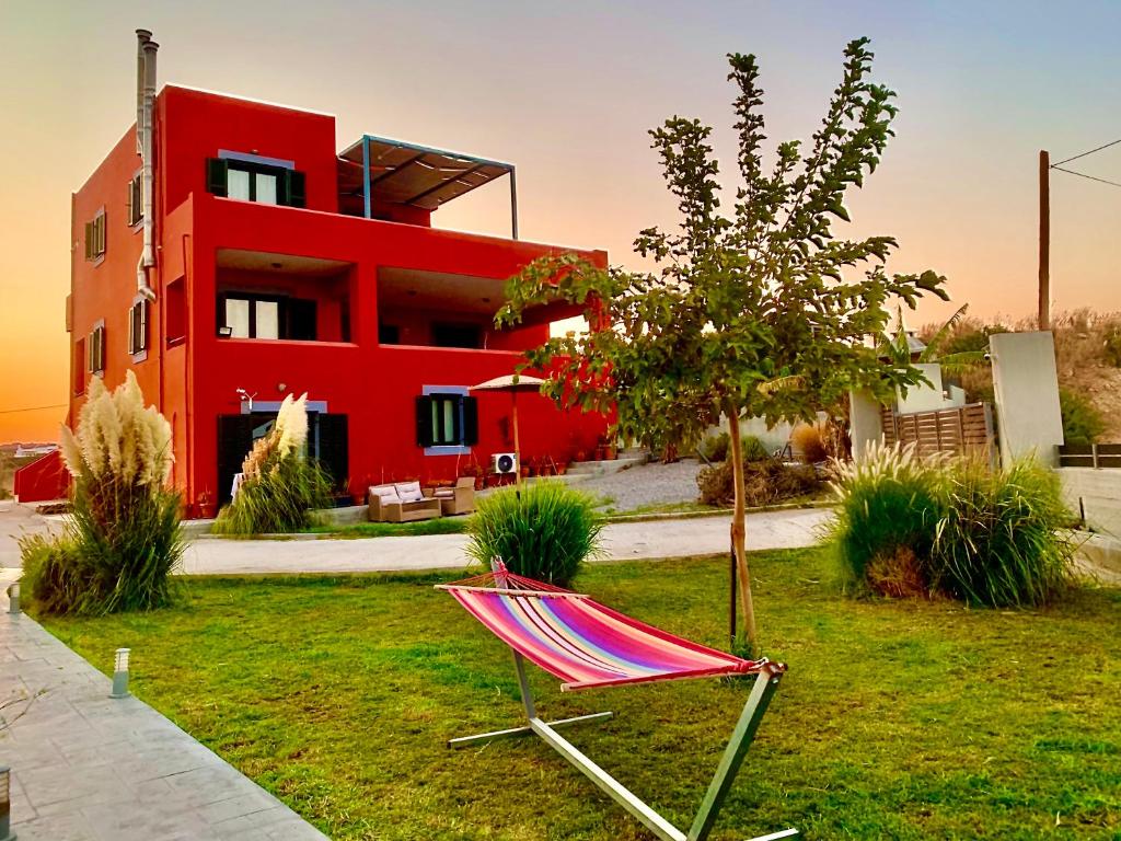 a red house with a chair in front of it at Helios Apartments - Beach of Lachania Rhodes in Lakhania