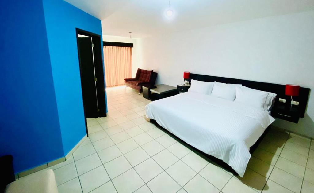 a bedroom with a white bed and a blue wall at Hotel Suites del Real in Guadalajara