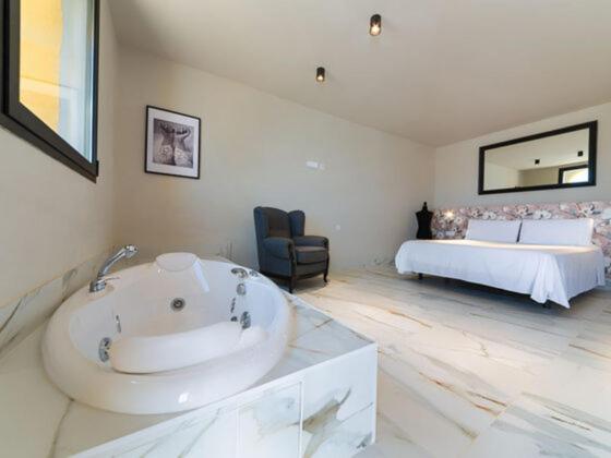 a large bathroom with a tub and a bed at Hacienda Soto-Hego Haizea in Chiclana de la Frontera