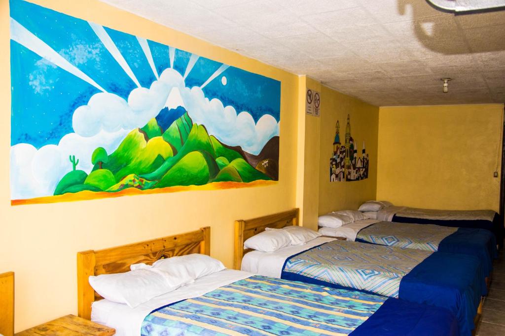 2 Betten in einem Zimmer mit Wandgemälde in der Unterkunft La Posada Del Viajero in Latacunga
