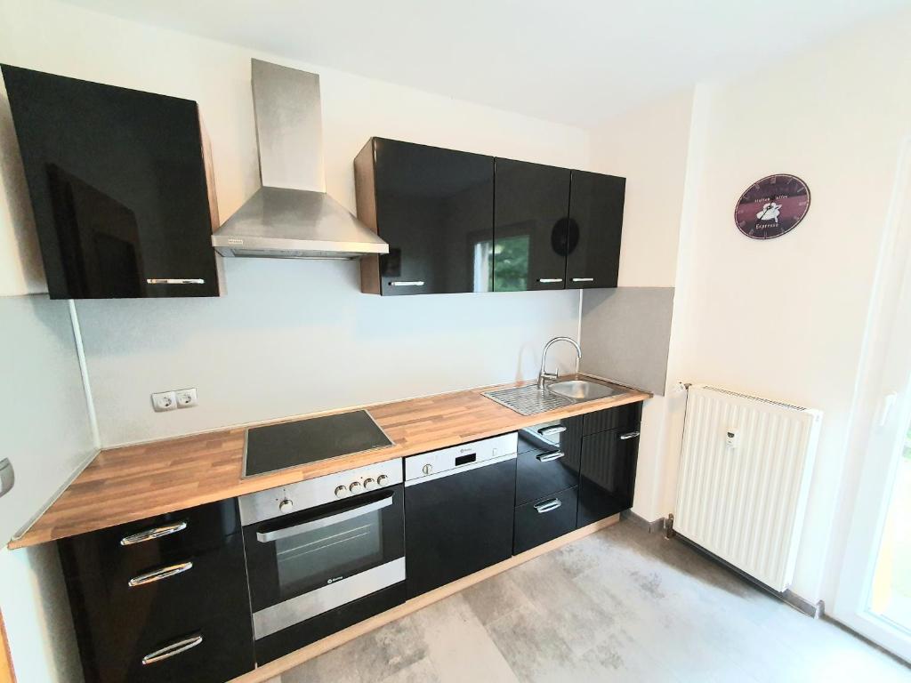 a kitchen with black cabinets and a wooden counter top at Lieblingsmensch Oberhausen mit Terrasse in Oberhausen