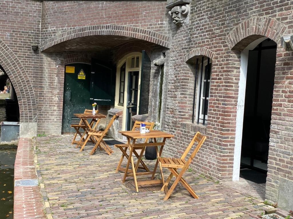 3 tables en bois assises à l'extérieur d'un bâtiment en briques dans l'établissement Slapen onder de Dom, à Utrecht