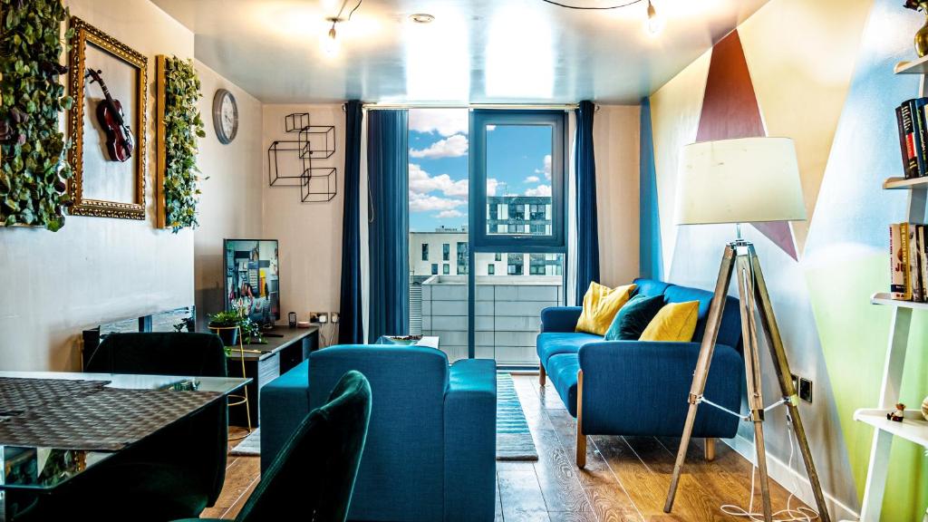 a living room with a blue couch and a large window at Beyond Blonk Apartments in Sheffield