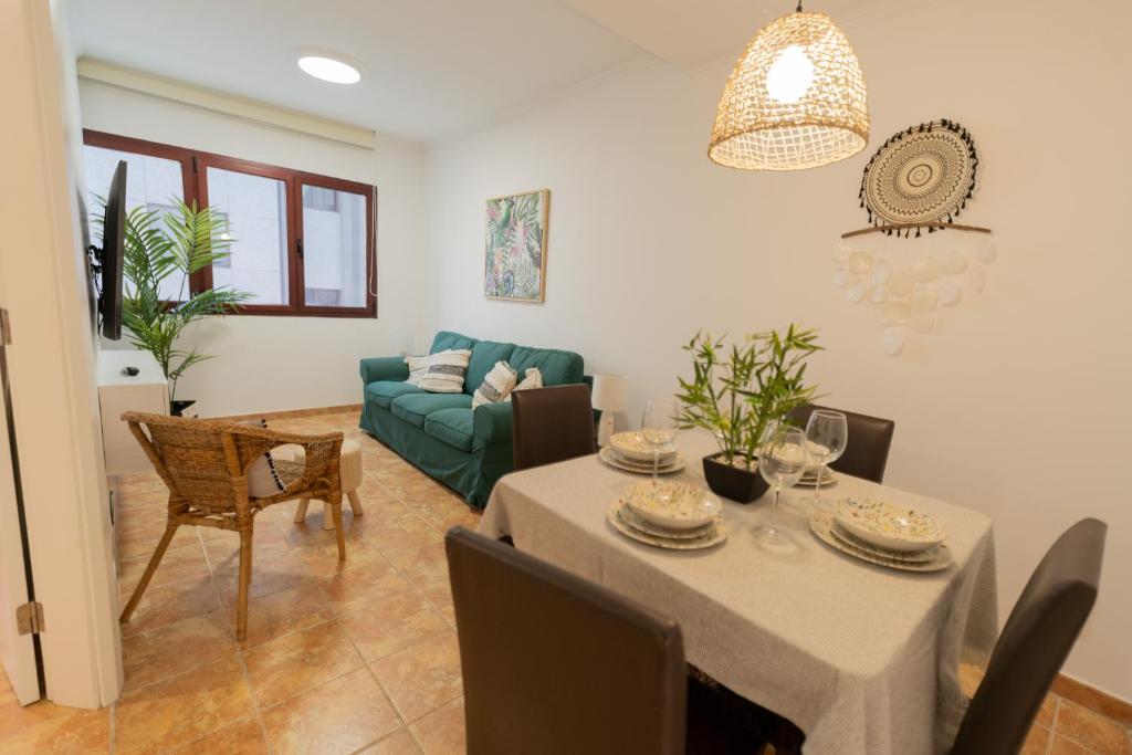 ein Wohnzimmer mit einem Tisch und einem grünen Sofa in der Unterkunft Agüita Surf Lodge in Las Palmas de Gran Canaria