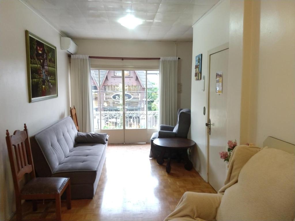 a living room with a couch and chairs and a window at Apartamento Augusto Zatti no centro in Gramado