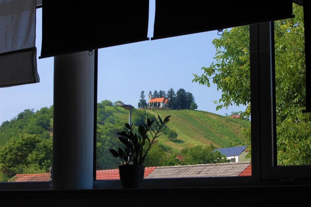 a window with a view of a house on a hill at Fado Apartments Lendava in Lendava