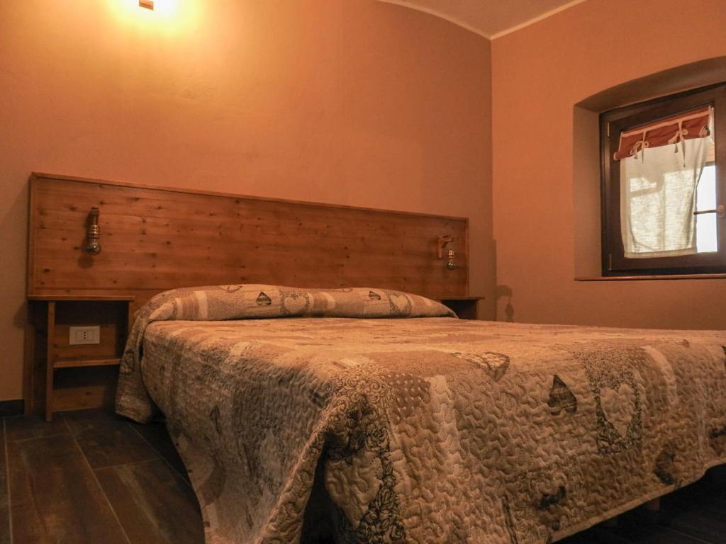 a bedroom with a bed with a wooden headboard and a window at La terrazza in Giaveno