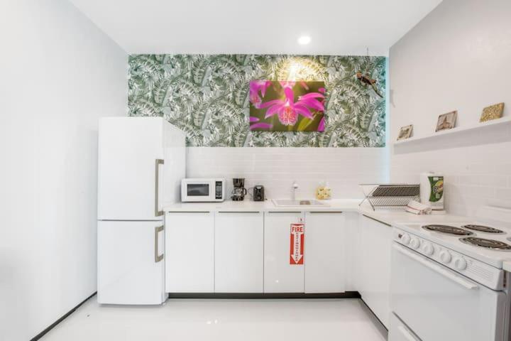 a white kitchen with white appliances and a painting on the wall at Las Olas Hammocks Unit 2 By Pmi in Fort Lauderdale