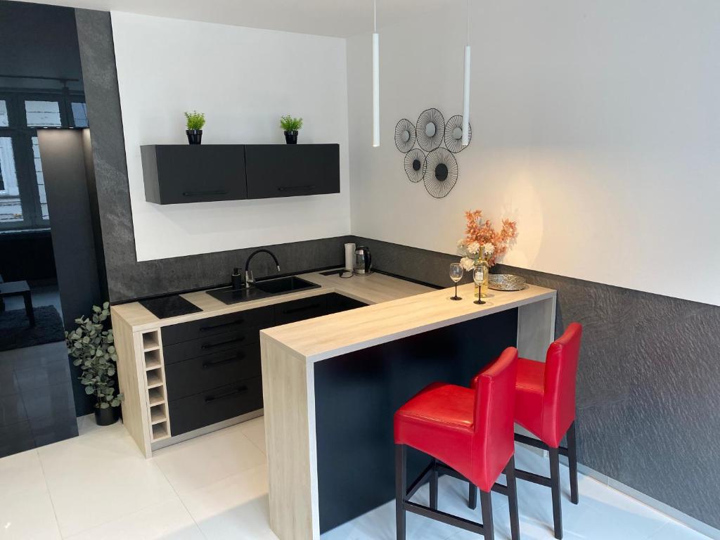 a kitchen with a sink and two red chairs at Apartamenty Planeta in Bielsko-Biala