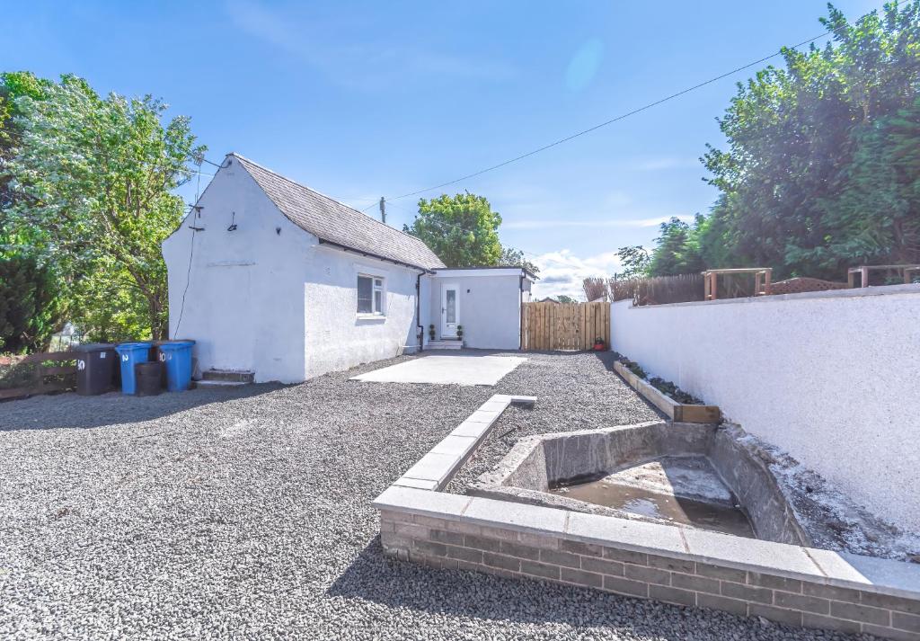 a backyard with a white building and a driveway at Lovely 1-Bed Cottage in Kelty with Hot Tub in Kelty