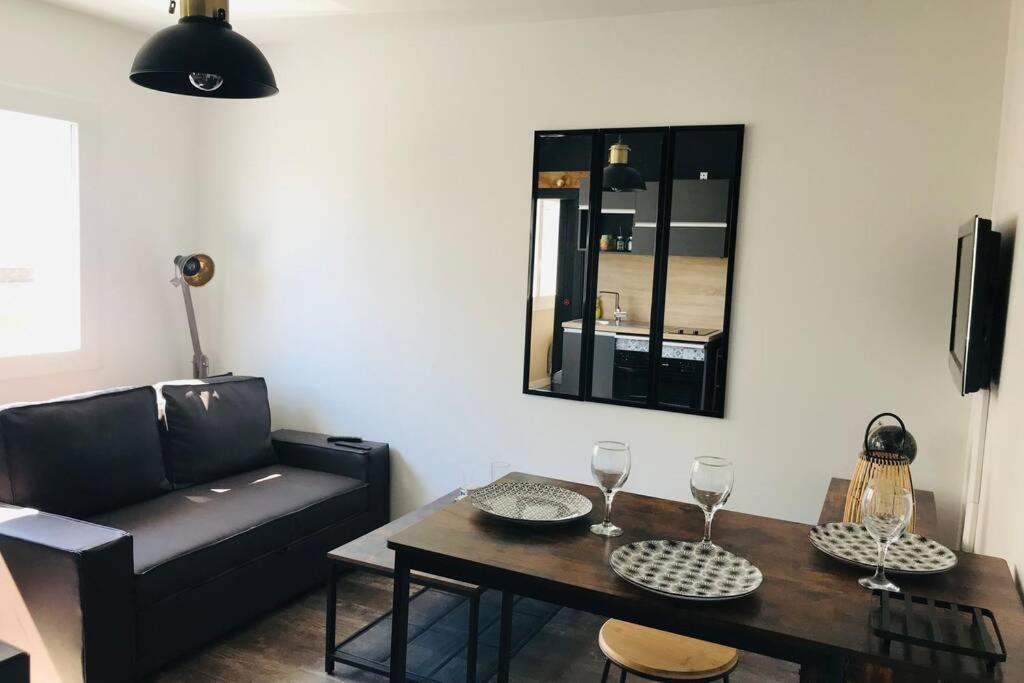 uma sala de estar com uma mesa e um sofá em Appartement 2/3 pers, centre ville avec parking. em Saint-Brévin-les-Pins