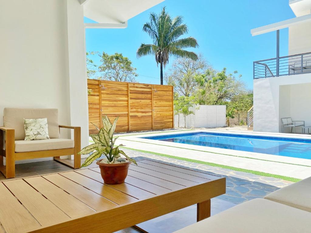 a villa with a swimming pool and a wooden table at Nicoya Villas in Mal País