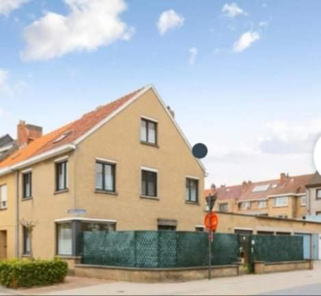 a house with a green fence in front of it at Casa Milex in De Panne