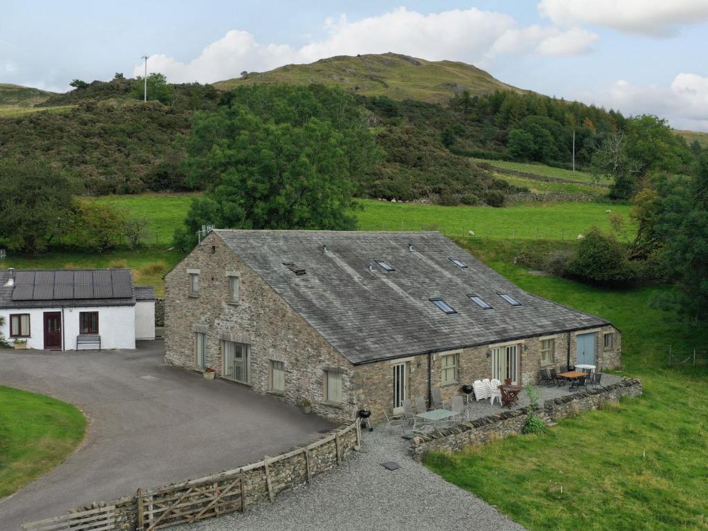 an old stone building with a driveway and a house at Ghyll Bank Byre in Staveley