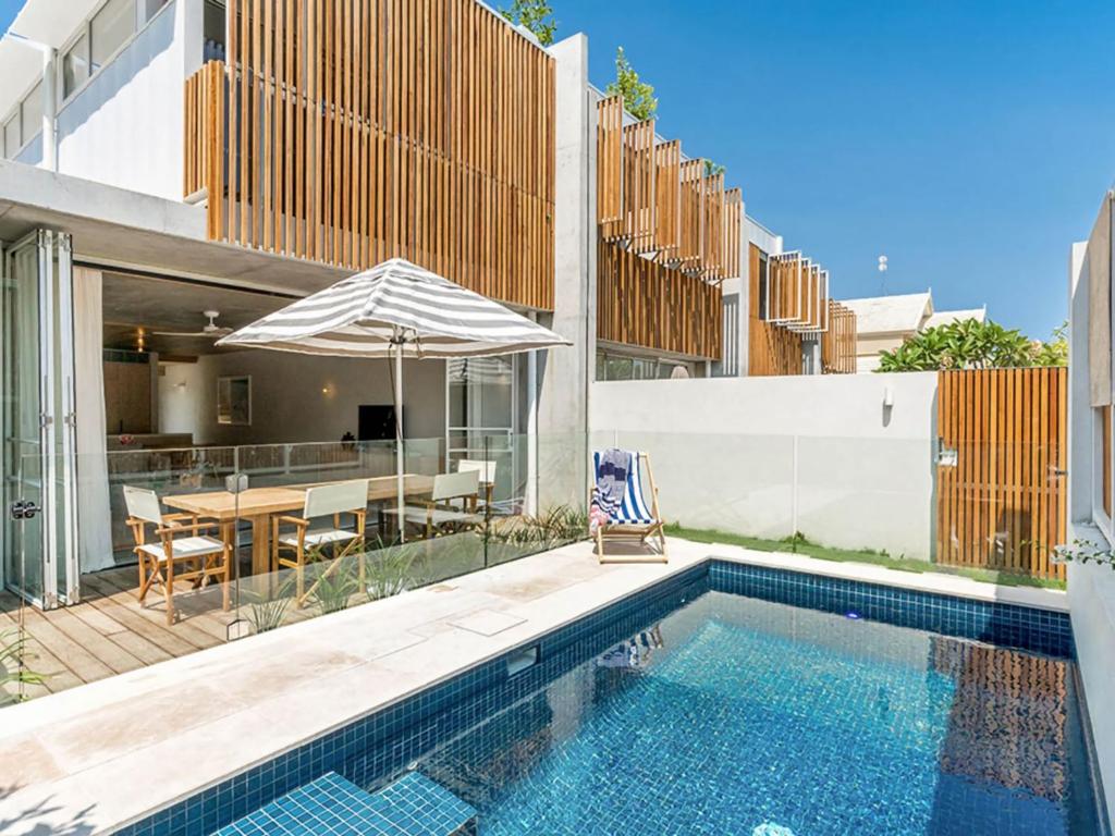 a house with a swimming pool and a table with an umbrella at Driftwood Three At Clarkes Beach in Byron Bay
