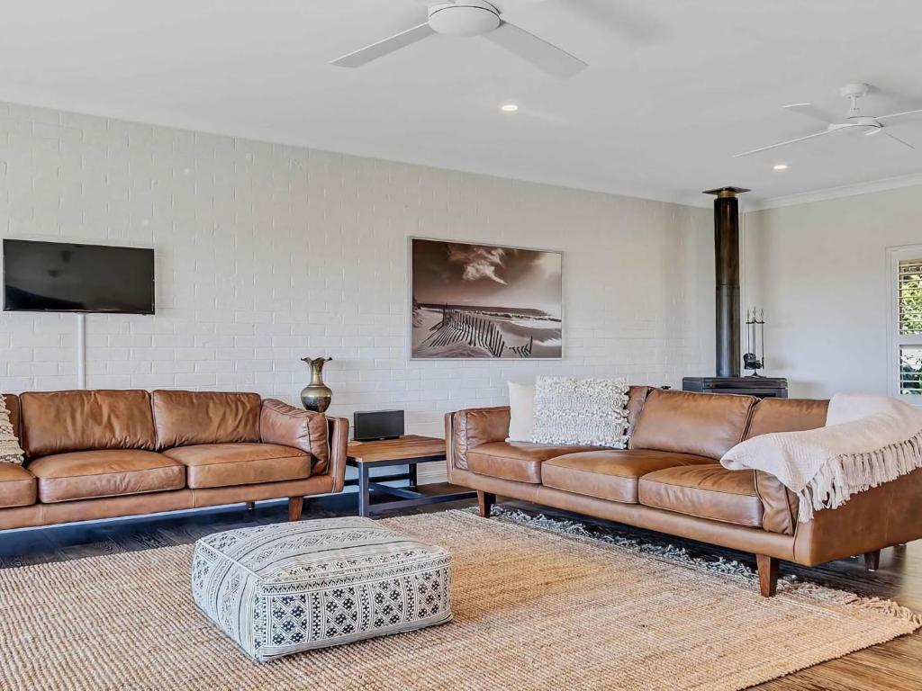 a living room with two leather couches and a table at Pauls Farmhouse in Newrybar