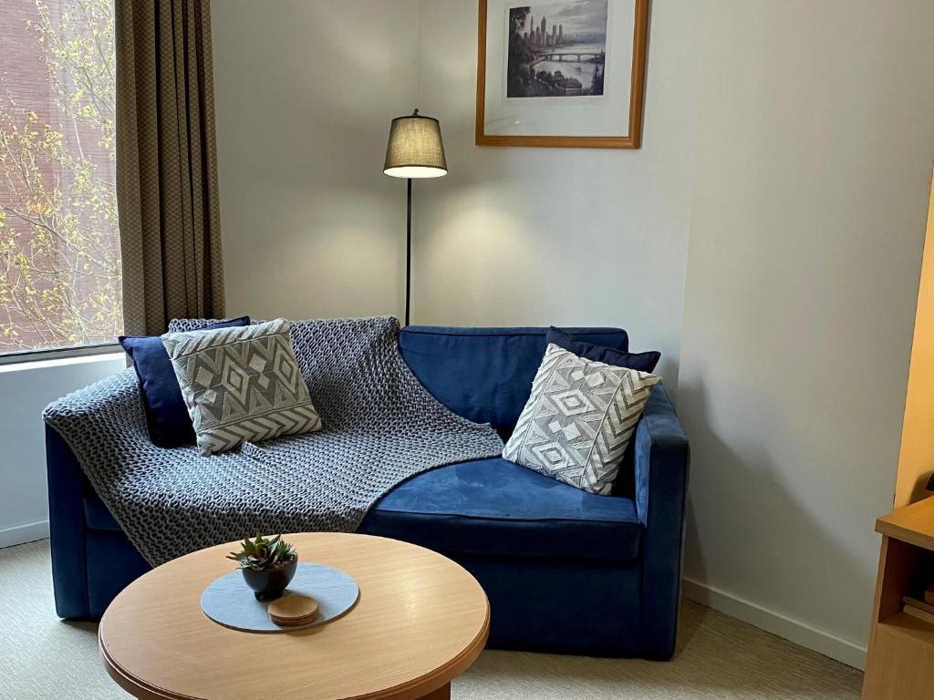 - un salon avec un canapé bleu et une table dans l'établissement 203 Cute As A Button Wkitchen For 2cbd, à Perth