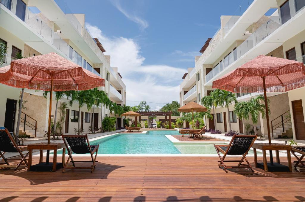 a swimming pool with chairs and umbrellas next to a building at Apartment and Penthouse Blue Luxury Kukulkan Tulum in Tulum