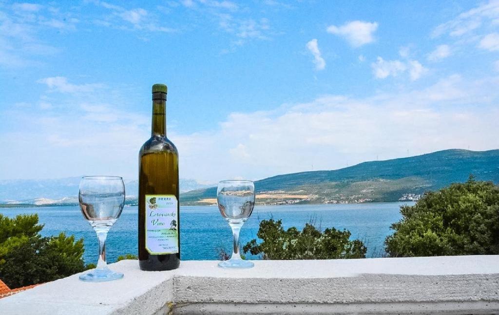a bottle of wine and two wine glasses on a ledge at Apartments Niko - 40m from the beach in Donji Karin