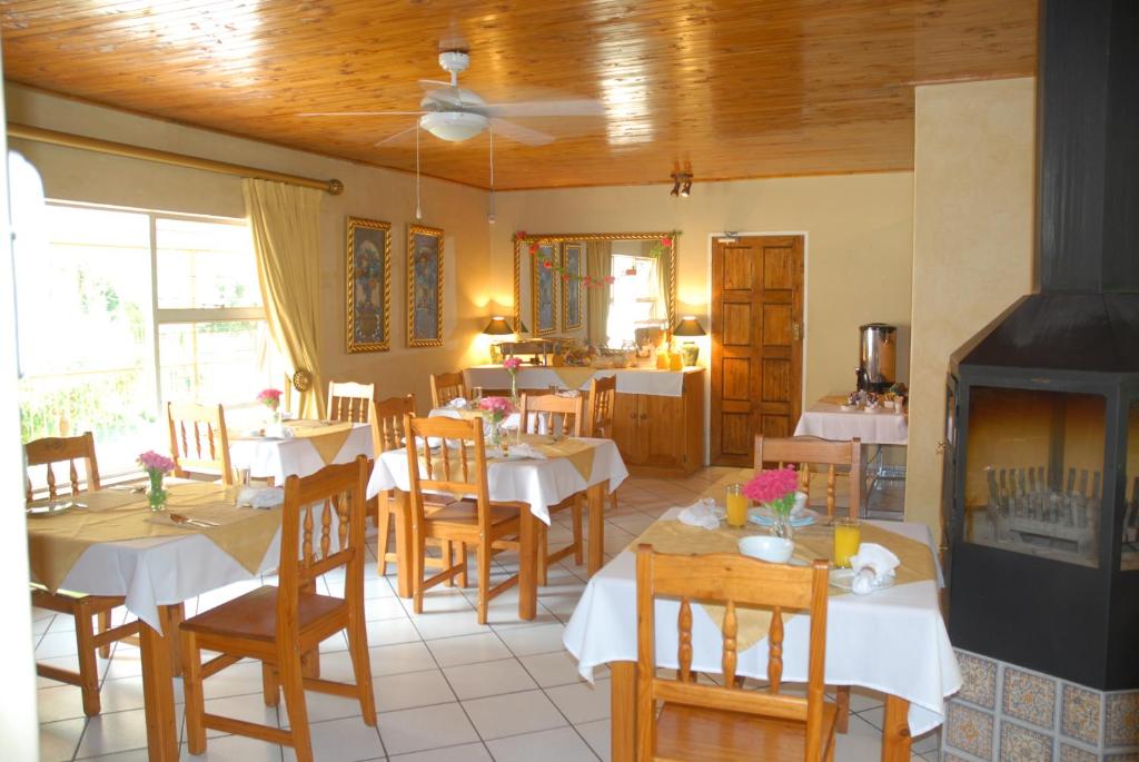 a dining room with white tables and wooden chairs at Purple Olive Guest House in Pretoria